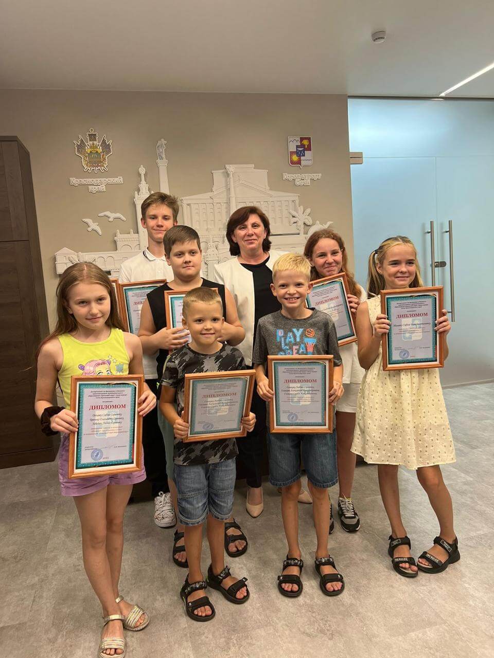 Дети с грамотами позируют вместе с директором департамента по финансам и бюджету города Сочи