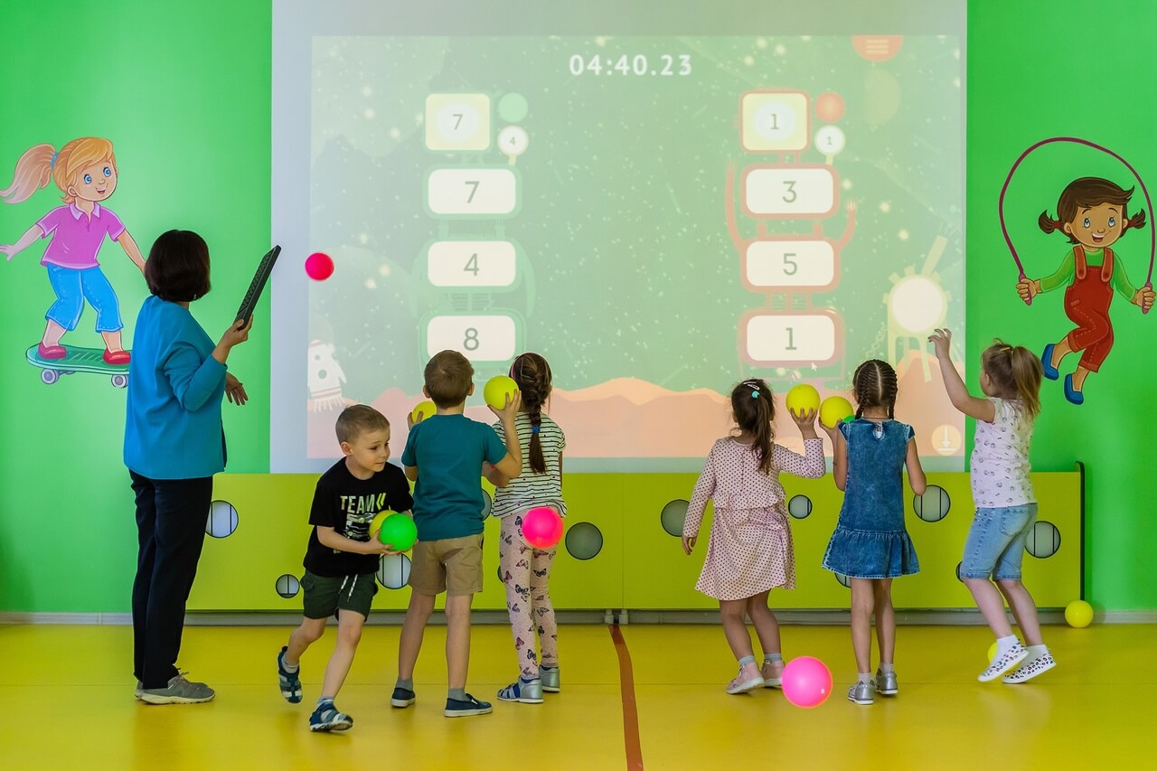 На фото дети бегают около интерактивной стены