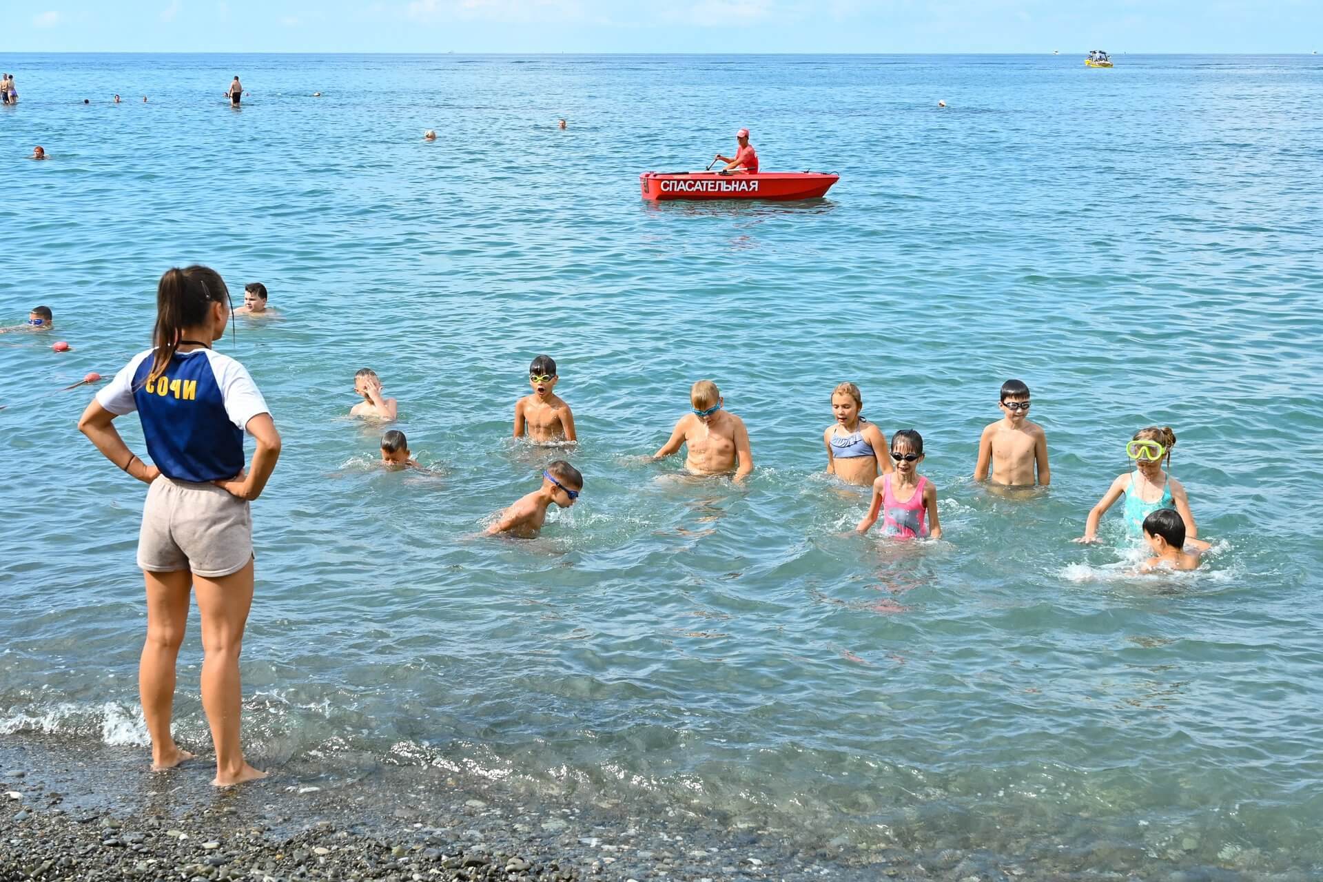 На фото детей в море инструктирует спасатель
