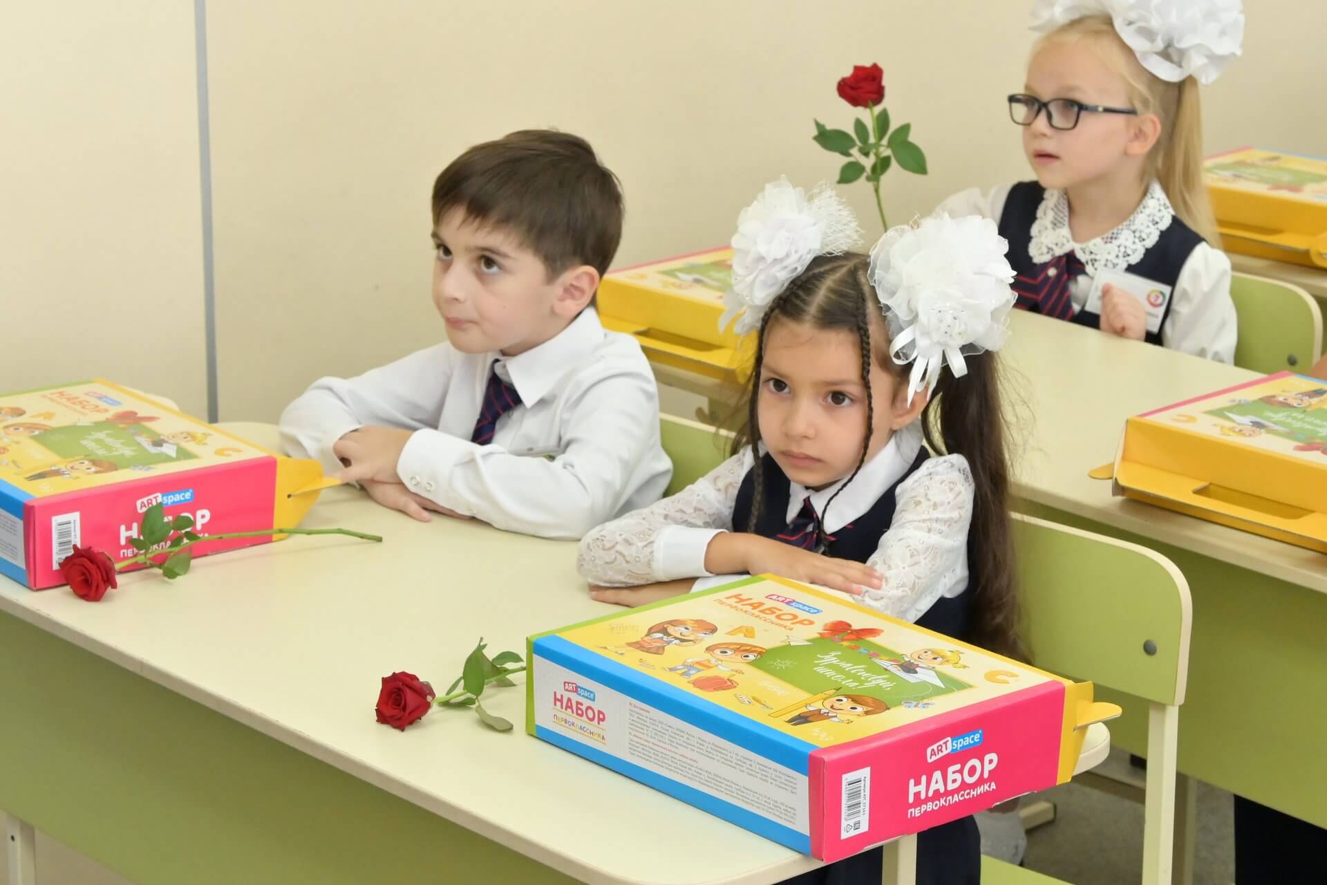 На фото первоклассники сидят за партой на 1 сентября