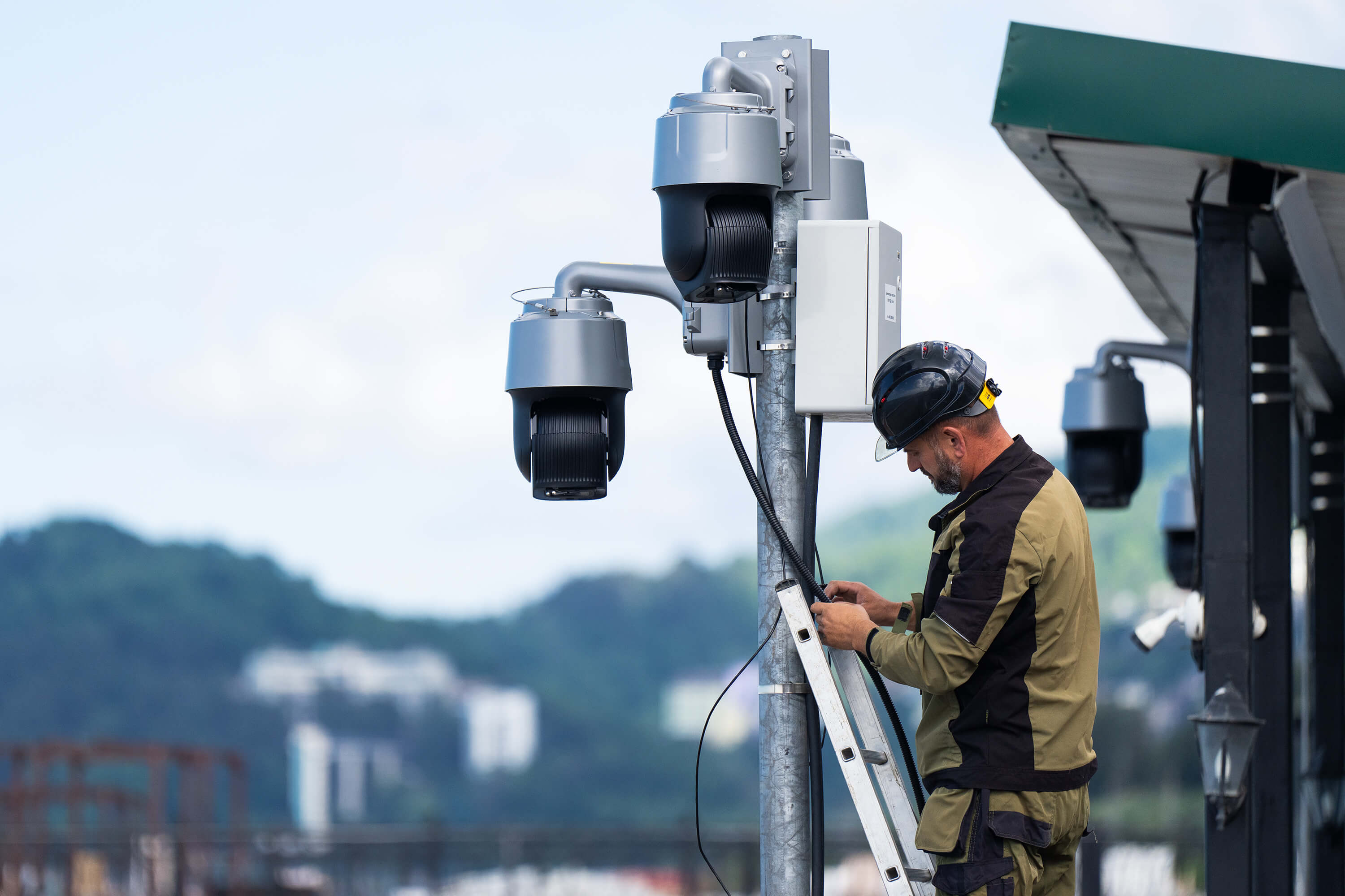 На фото мастер устанавливает городские камеры видеонабюлдения