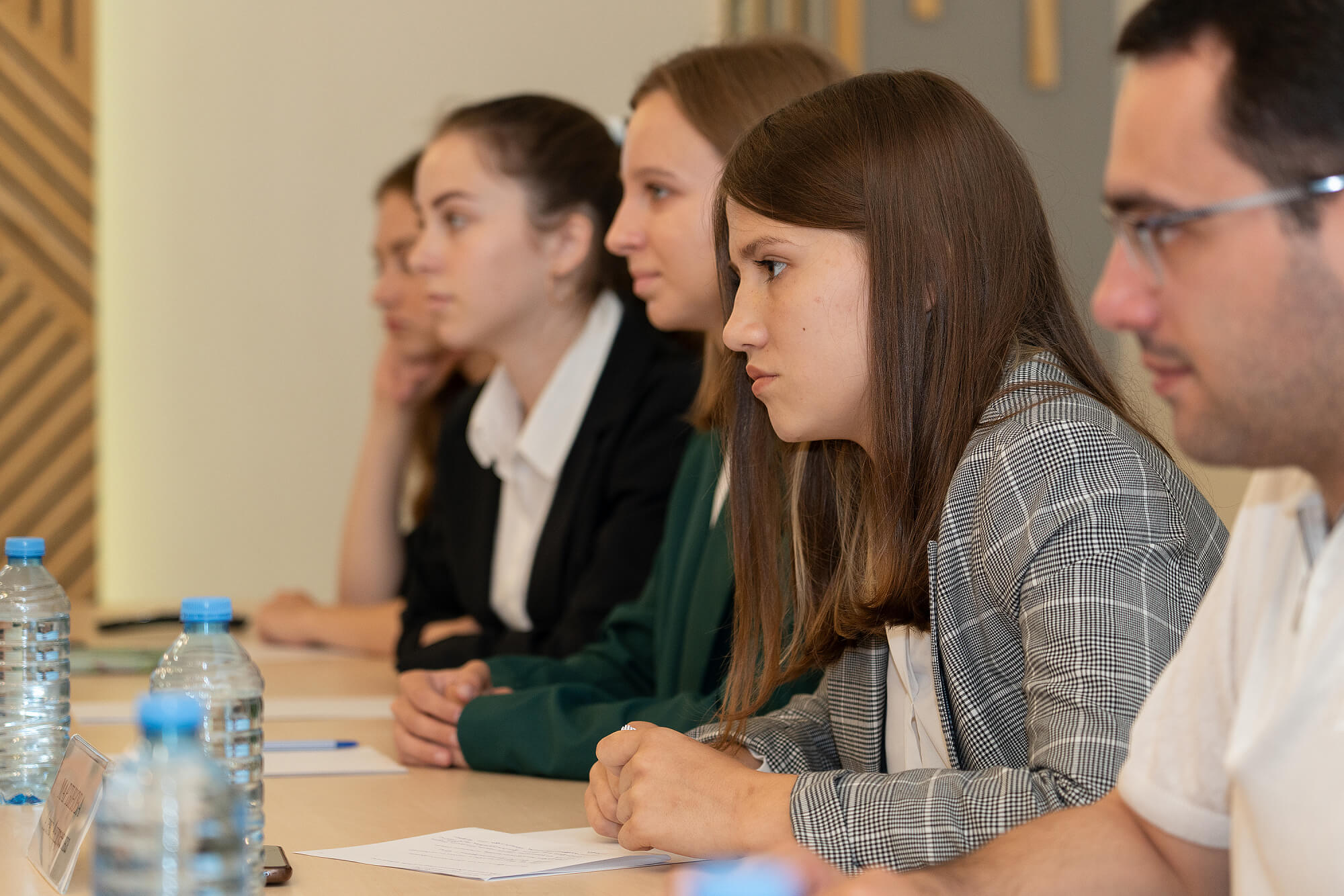 На фото молодежь Сочи сидит за столом и записывает